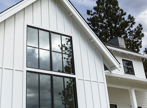 Exterior view of a modern farmhouse with vertical paneling and black window trim