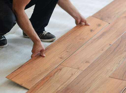 Laying down slats of laminate flooring on an angle to fit into the tongue grooves