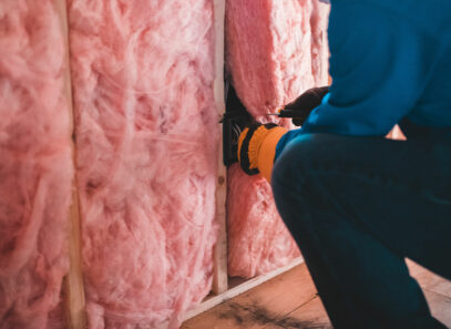 A batt of blanket insulation is rolled out between rafters in an attic.